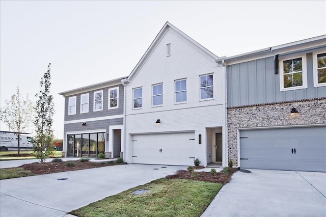 view of front facade featuring driveway, an attached garage, board and batten siding, and brick siding