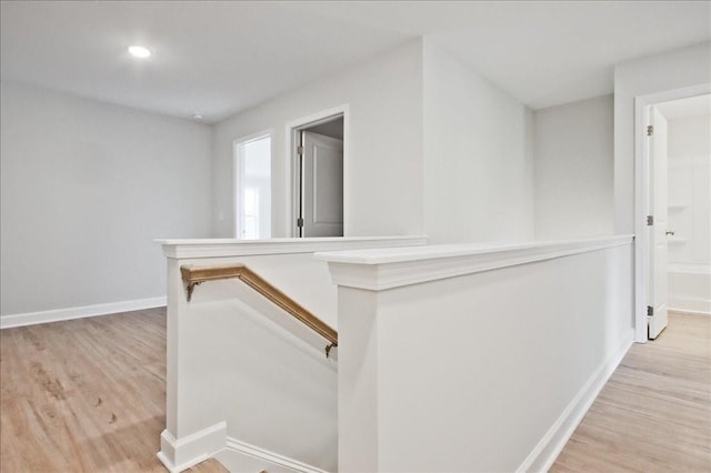 hallway with light wood-type flooring, recessed lighting, baseboards, and an upstairs landing