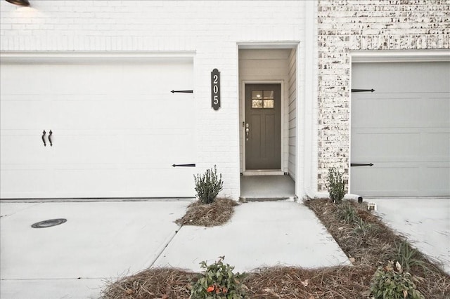 entrance to property with a garage and brick siding