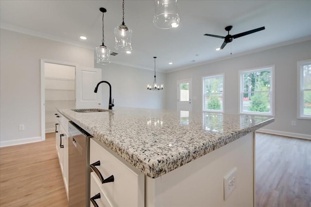 kitchen with stainless steel dishwasher, a sink, white cabinets, and crown molding