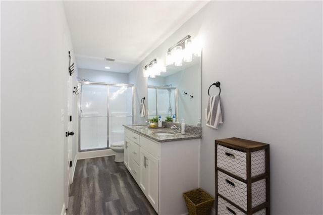 bathroom with wood-type flooring, toilet, a shower with door, and vanity