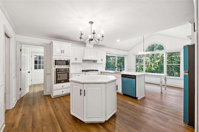 kitchen featuring hanging light fixtures, vaulted ceiling, appliances with stainless steel finishes, a kitchen island, and white cabinetry