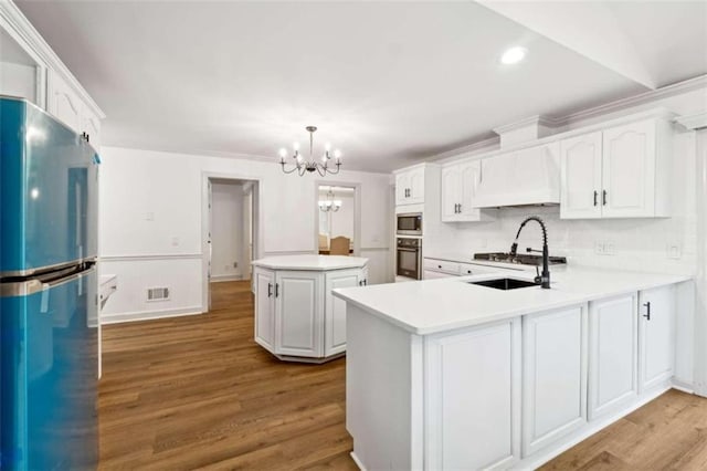 kitchen featuring light hardwood / wood-style floors, kitchen peninsula, premium range hood, and appliances with stainless steel finishes