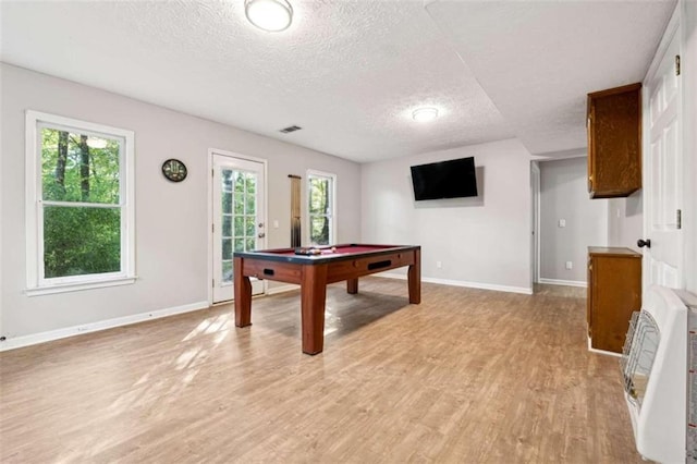 rec room featuring heating unit, a wealth of natural light, light hardwood / wood-style flooring, and a textured ceiling