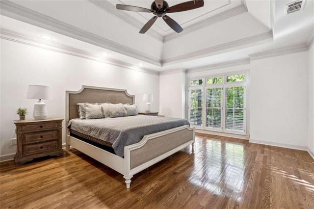 bedroom featuring a tray ceiling, ceiling fan, dark hardwood / wood-style flooring, and ornamental molding