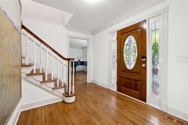 foyer with a wealth of natural light, ornamental molding, and hardwood / wood-style flooring