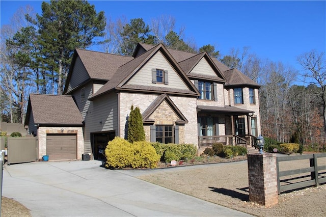 view of front of home with driveway, a garage, covered porch, fence, and brick siding