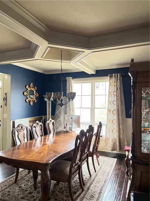 dining room with coffered ceiling, crown molding, hardwood / wood-style floors, and an inviting chandelier