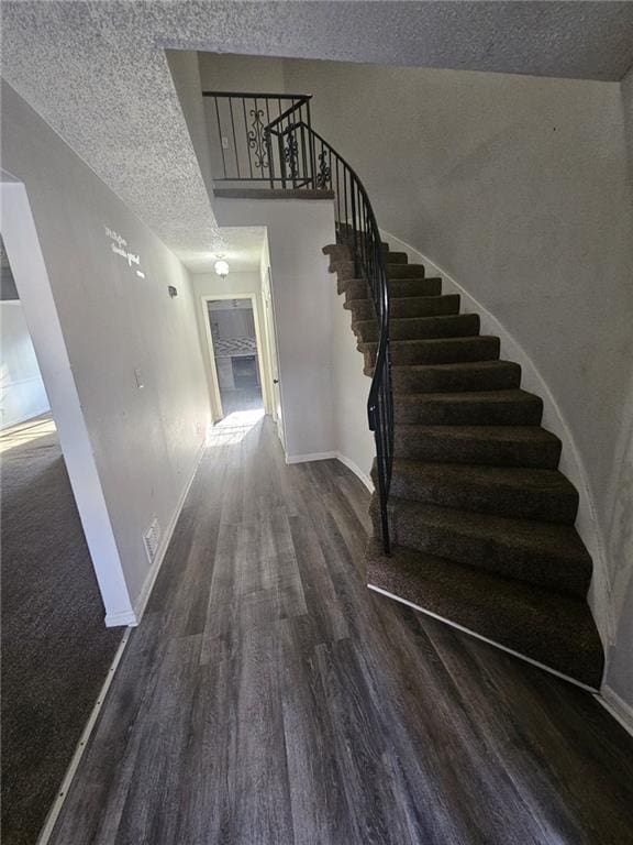 stairway with hardwood / wood-style floors and a textured ceiling