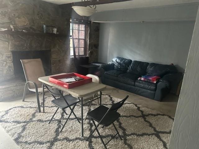 living room featuring a stone fireplace and concrete floors