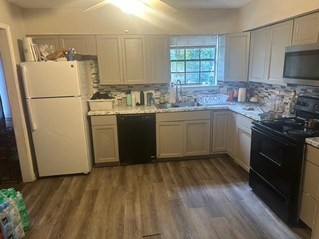 kitchen featuring dark wood-type flooring, sink, light stone counters, and black appliances