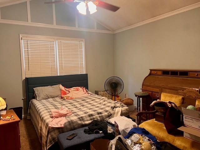 carpeted bedroom with ceiling fan, vaulted ceiling, and ornamental molding