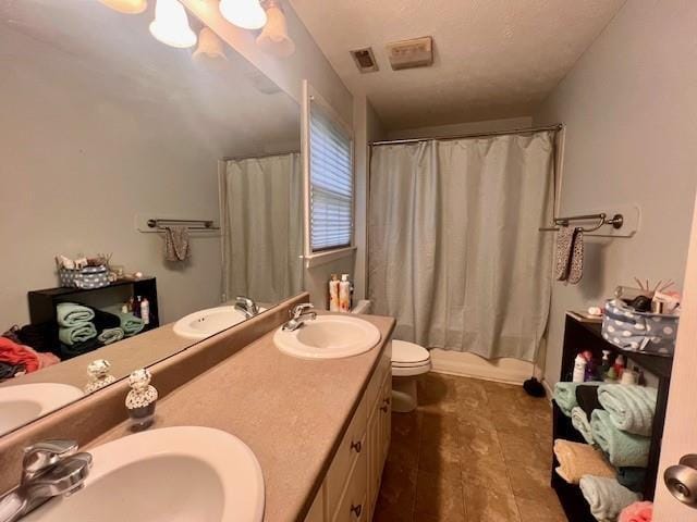 bathroom with a sink, toilet, double vanity, and visible vents