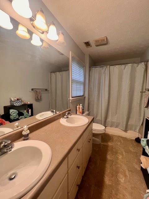 full bath with visible vents, a sink, tile patterned floors, and toilet