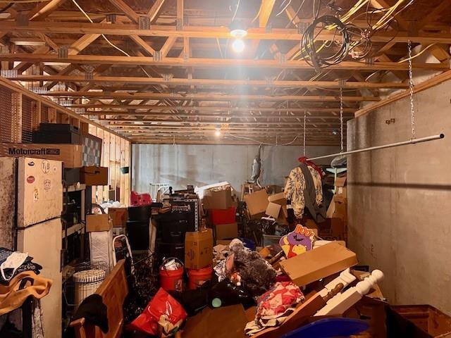 unfinished basement with freestanding refrigerator