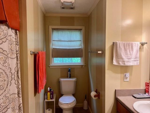 bathroom featuring vanity, crown molding, visible vents, and toilet