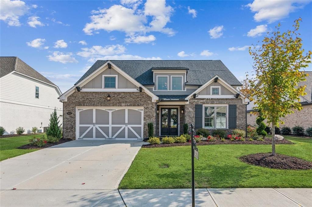 craftsman-style home featuring a front lawn, a garage, and french doors