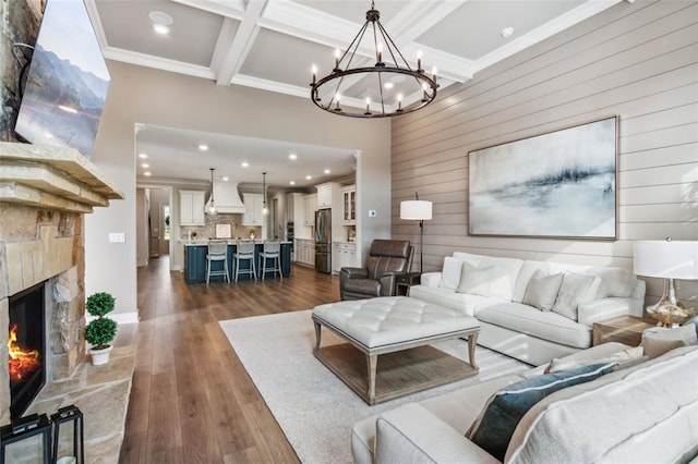 living room featuring dark hardwood / wood-style flooring, coffered ceiling, crown molding, beam ceiling, and a fireplace