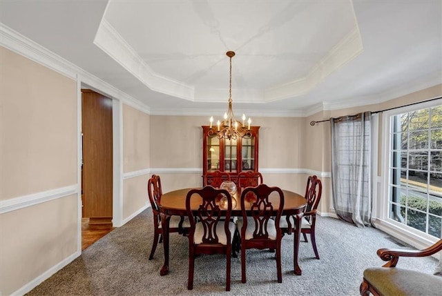 dining space featuring a chandelier, carpet flooring, a raised ceiling, and crown molding