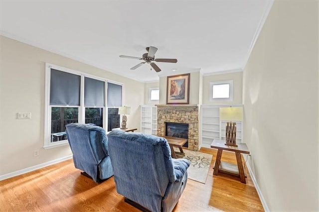 living room featuring hardwood / wood-style flooring, a stone fireplace, ceiling fan, and ornamental molding