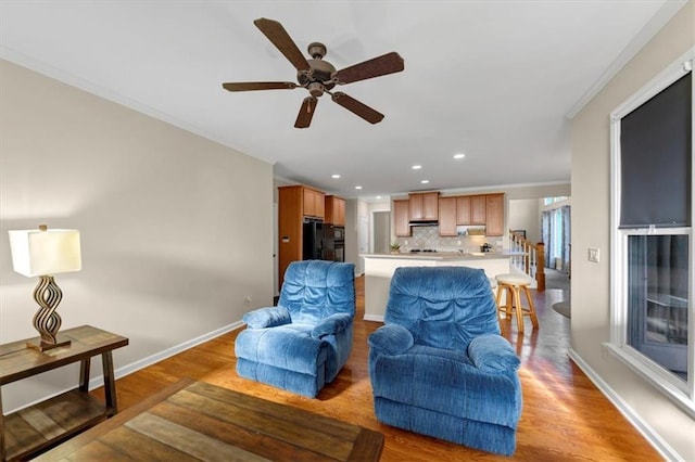 living room featuring ceiling fan, light hardwood / wood-style floors, and crown molding