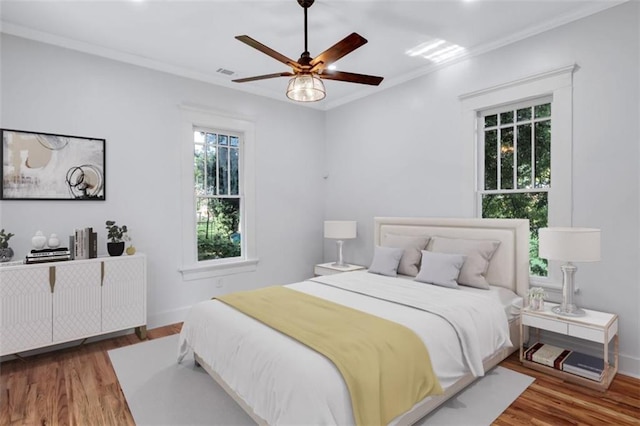 bedroom with ceiling fan, hardwood / wood-style floors, and ornamental molding