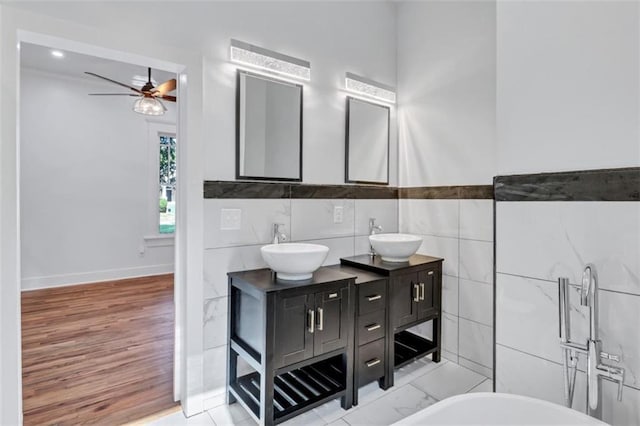 bathroom featuring ceiling fan, tile walls, vanity, and a bathing tub