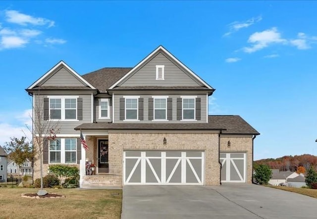 view of front facade featuring a front yard, roof with shingles, an attached garage, concrete driveway, and brick siding