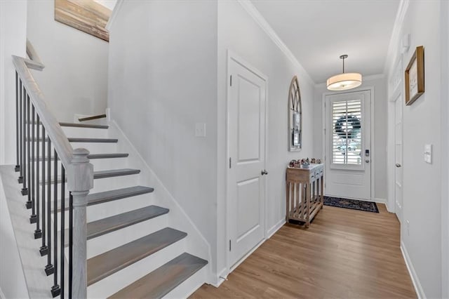 entrance foyer with stairway, baseboards, wood finished floors, and crown molding