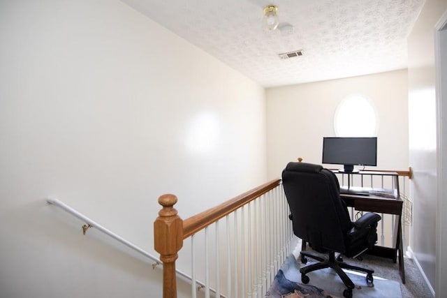 office area with carpet floors, a textured ceiling, and visible vents