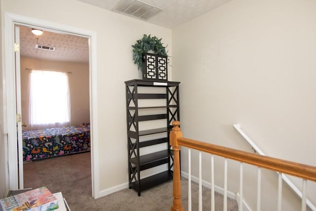 hallway featuring visible vents, carpet flooring, baseboards, and an upstairs landing