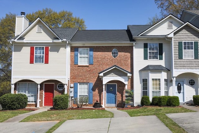 view of property with brick siding, a chimney, and a front yard