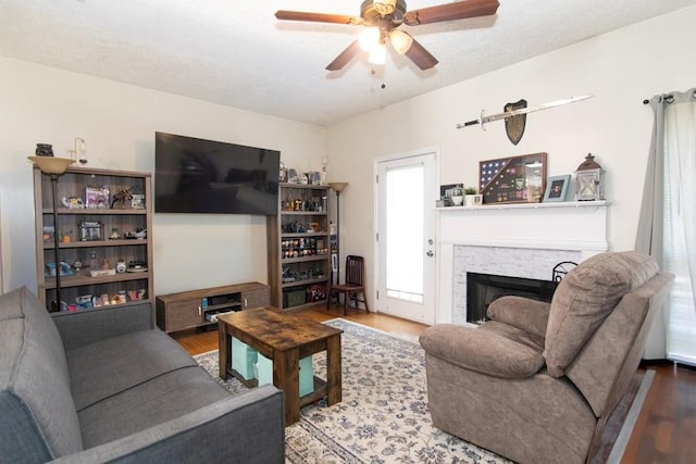living room featuring a ceiling fan, wood finished floors, and a fireplace