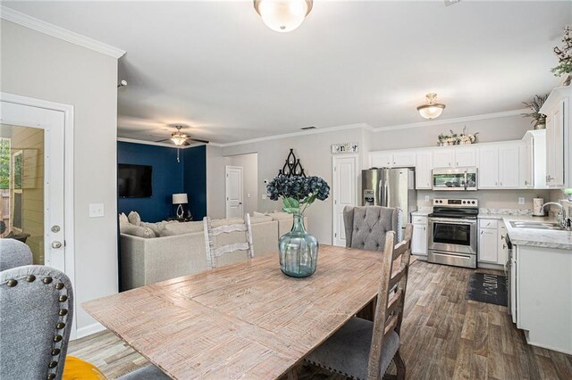 dining area with ceiling fan, dark wood finished floors, and ornamental molding
