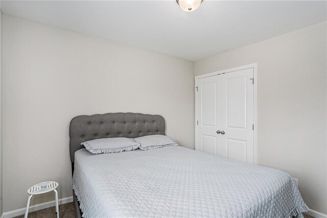 carpeted bedroom featuring baseboards and a closet