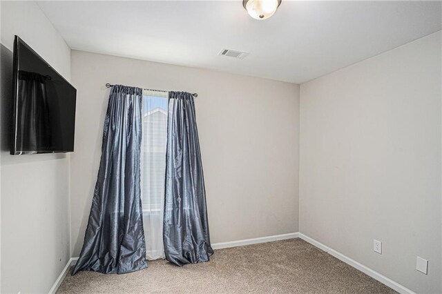 carpeted empty room featuring baseboards and visible vents