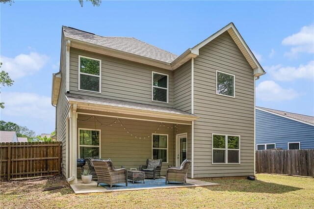 rear view of property featuring a fenced backyard, roof with shingles, an outdoor hangout area, a patio area, and a lawn