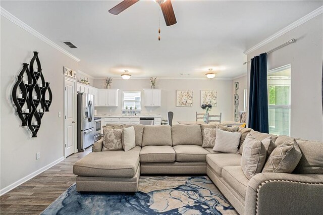 living room featuring visible vents, crown molding, wood finished floors, baseboards, and ceiling fan