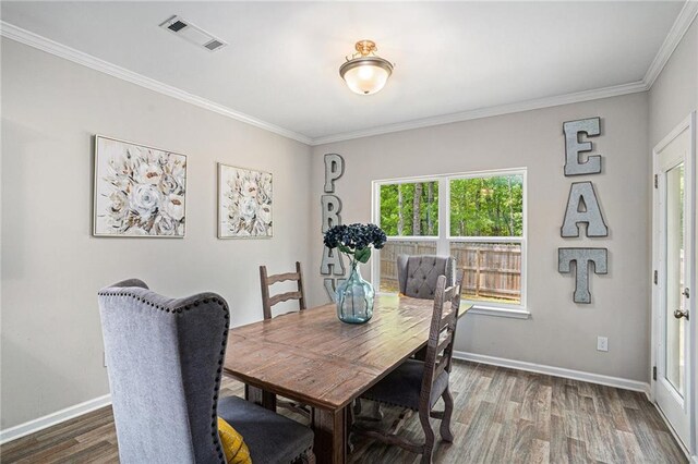 dining room with baseboards, visible vents, ornamental molding, and wood finished floors
