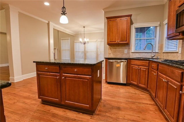 kitchen featuring sink, hanging light fixtures, ornamental molding, a center island, and stainless steel appliances