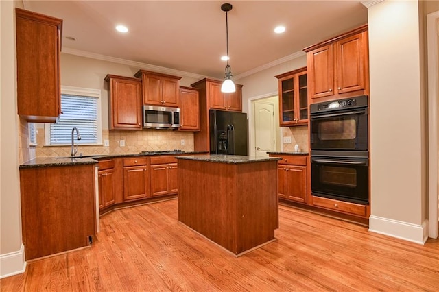 kitchen with sink, light wood-type flooring, dark stone countertops, a kitchen island, and black appliances