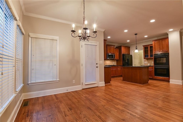 kitchen featuring a kitchen island, decorative light fixtures, ornamental molding, light hardwood / wood-style floors, and black appliances