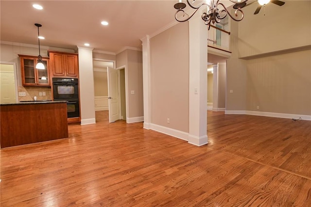 kitchen featuring crown molding, decorative light fixtures, black double oven, and light wood-type flooring