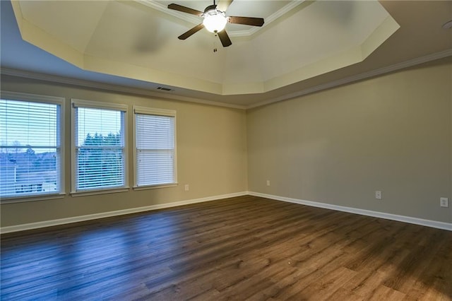 empty room with dark wood-type flooring, ornamental molding, a raised ceiling, and ceiling fan