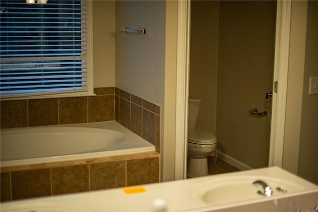 bathroom featuring tiled tub and toilet