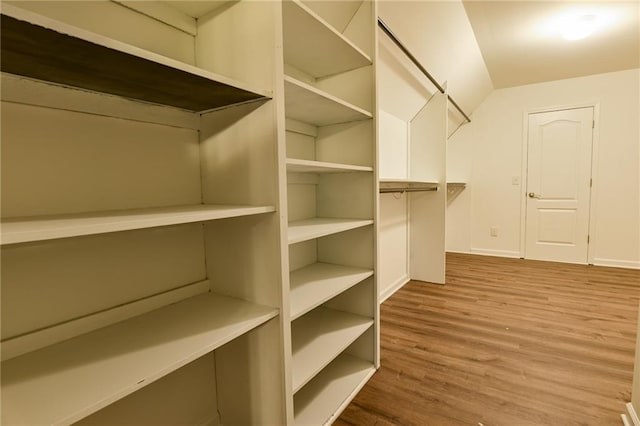 walk in closet with vaulted ceiling and hardwood / wood-style floors