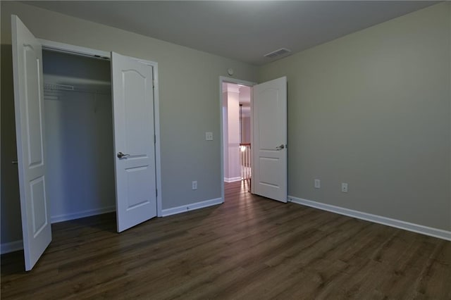 unfurnished bedroom with dark hardwood / wood-style flooring and a closet