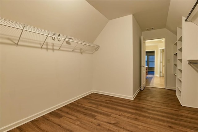 spacious closet with lofted ceiling and dark hardwood / wood-style flooring