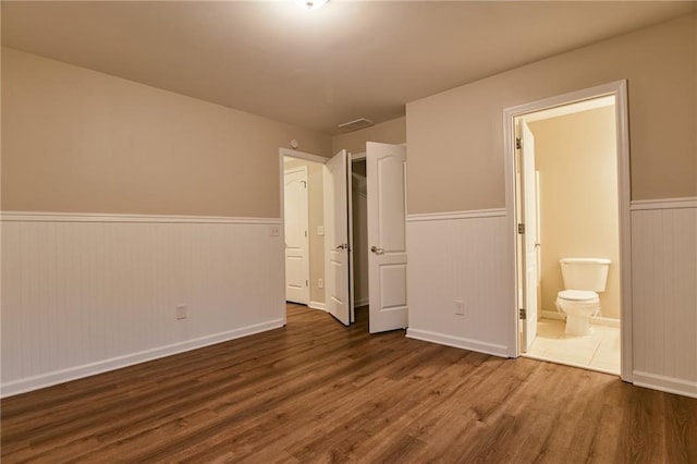 unfurnished bedroom with connected bathroom and dark hardwood / wood-style flooring