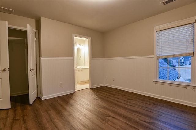 unfurnished bedroom with ensuite bath and dark hardwood / wood-style floors